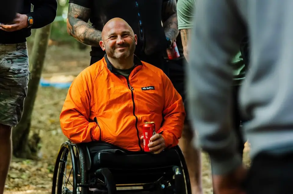 An attendee in a bright jacket smiling while standing near the fire.