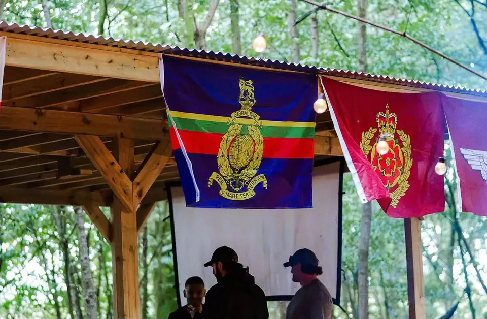 Regimental flags hung between trees at the edge of the gathering.